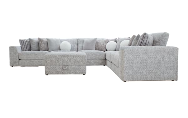Large L-shaped sectional sofa upholstered in light gray textured fabric with matching ottoman and multiple decorative cushions in various gray tones and patterns, designed for spacious living room seating and comfort.