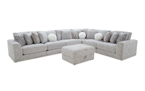 Light gray fabric sectional sofa with plush cushions and matching ottoman, featuring a modern design ideal for spacious living rooms.
