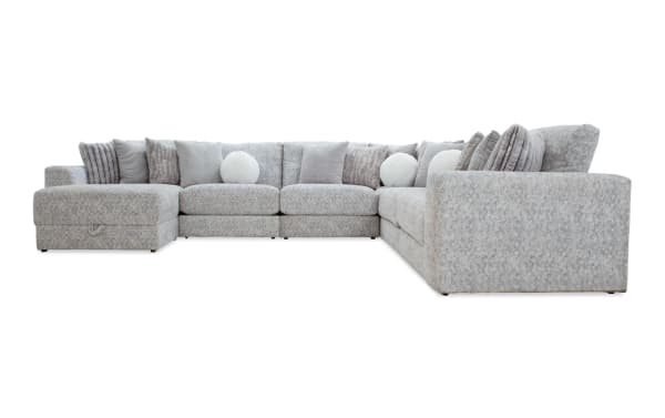 Large L-shaped sectional sofa upholstered in light gray textured fabric with multiple matching and round white throw pillows, designed for spacious living rooms.