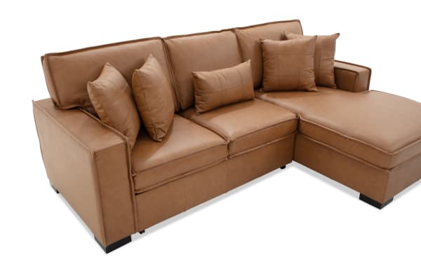 Modern L-shaped sectional sofa in tan brown faux leather with cushioned armrests, stitched detailing, and multiple matching throw pillows.