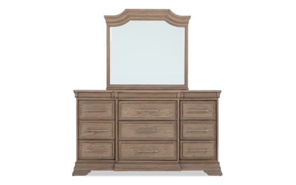 Wooden dresser with a large decorative mirror, featuring nine drawers with metal handles in a rustic brown finish, ideal for bedroom storage.