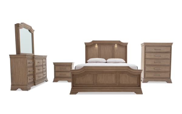 Traditional style bedroom set in light brown wood finish, featuring a king-size bed with paneled headboard and footboard, matching dresser with mirror, nightstand, and chest of drawers. The furniture showcases classic carved details and metal handles, designed for a cohesive and elegant bedroom decor.