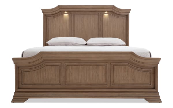 King-size wooden bed frame in warm brown finish with paneled headboard and footboard, featuring built-in overhead reading lights and classic molding details.