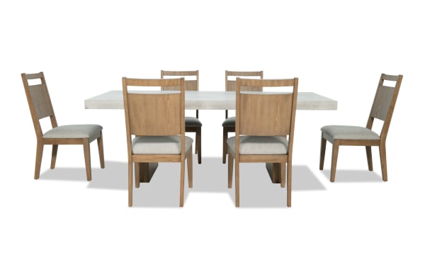 Monterey 7 Piece Natural & Gray Panel Back Upholstered Dining Set with faux concrete melamine table top and six gray fabric polyester chairs.