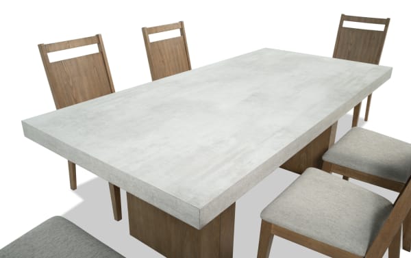 Monterey 7 Piece Natural & Gray Panel Back Upholstered Dining Set with faux concrete melamine tabletop, gray polyester fabric chairs, and traditional wood frame.