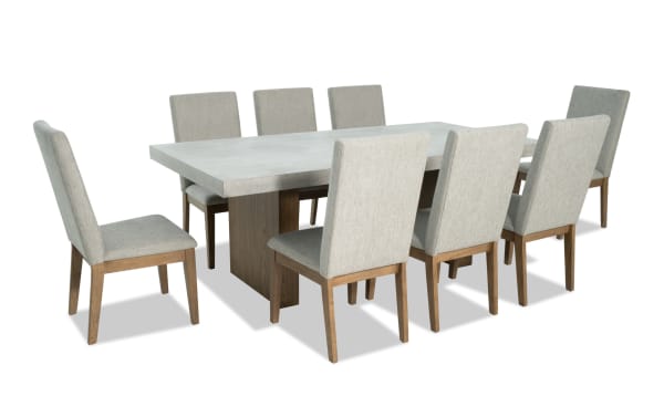 Monterey 9 Piece Natural & Gray Solid Back Upholstered Dining Set with faux concrete melamine table top and eight gray polyester fabric chairs.
