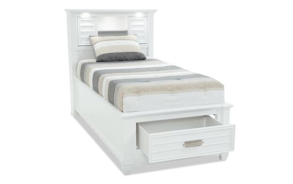 Sunset Cove Youth Twin White Bookcase Storage Bed in coastal style, MDF construction with built-in storage drawer, LED lighting, power outlets, and USB/USB-C ports in headboard.