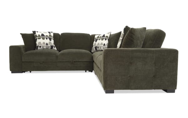 Dark olive green L-shaped sectional sofa with plush cushions and patterned throw pillows, featuring a modern, fabric upholstery and low block legs.