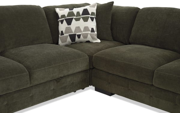 Dark olive green sectional sofa with plush cushions and a decorative geometric-patterned throw pillow, featuring soft fabric upholstery and modern design.