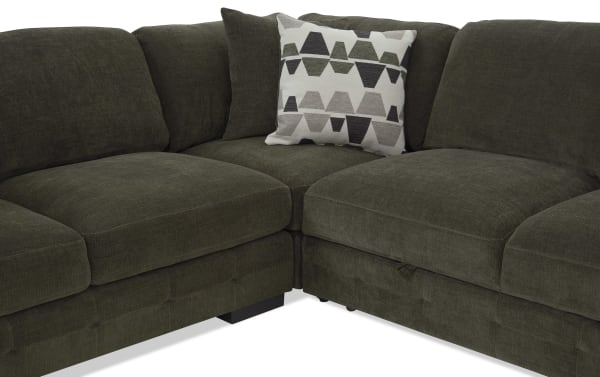 Dark olive green sectional sofa with plush fabric upholstery, featuring thick cushions and a decorative geometric patterned throw pillow.