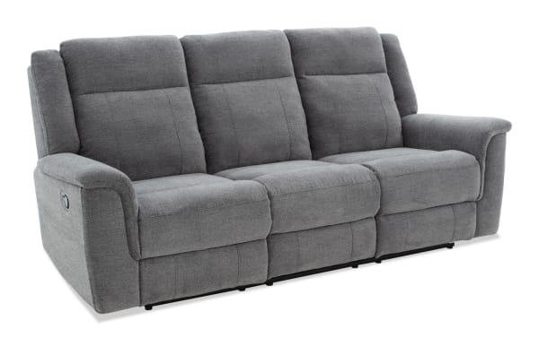 Gray fabric reclining sofa with three seats, padded armrests, and cushioned backrests, designed for living room comfort.