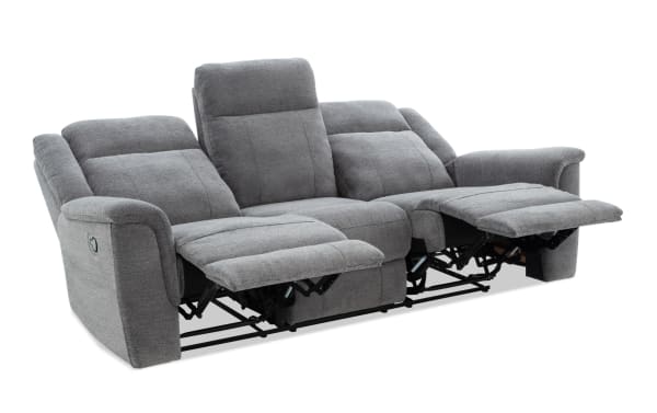 Gray fabric reclining sofa with three seats, two footrests extended, padded armrests, and cushioned backrests for living room comfort.