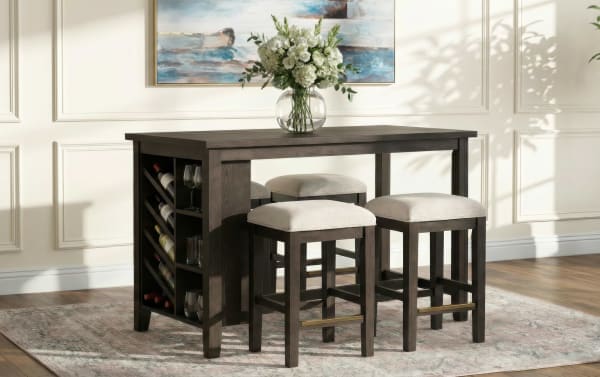 Dark wood dining table set with built-in wine rack, four cushioned beige stools, and a glass vase with white flowers, on a patterned rug.