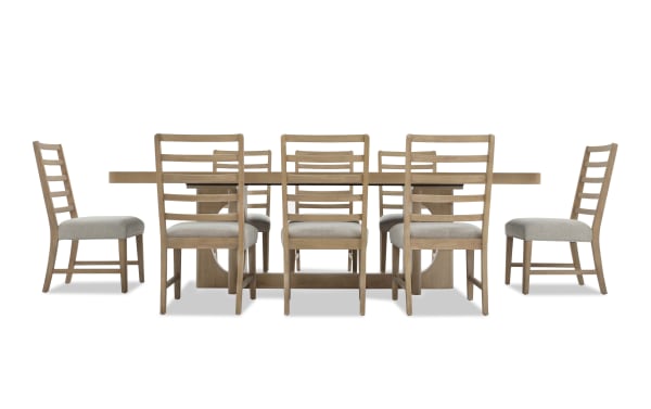 Solid wood rectangular dining table with a natural finish, paired with eight ladder-back chairs featuring beige cushioned seats and wooden frames.