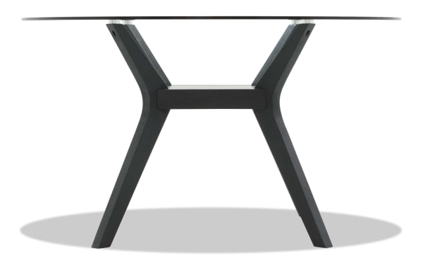 Modern round glass dining table with black wooden angled legs and central support beam, showcasing contemporary minimalist design.