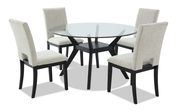 Round dining table set with a clear glass top and black wooden legs, paired with four beige upholstered chairs featuring black wooden frames.