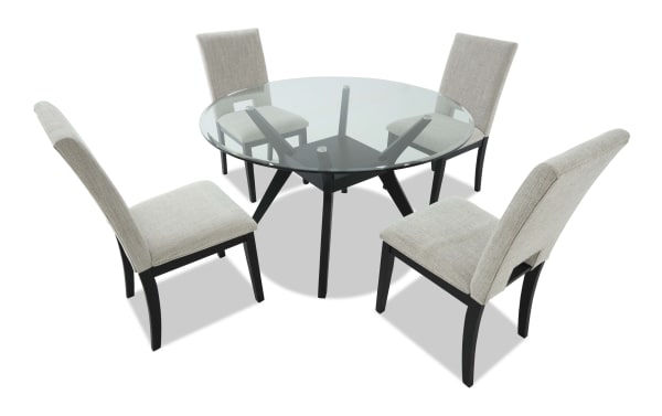 Round glass dining table with black metal legs and four beige upholstered chairs with black wooden legs, modern dining set.