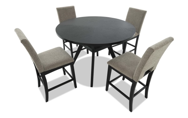 Round black wooden dining table with four beige upholstered chairs featuring black wooden legs, suitable for modern dining rooms.