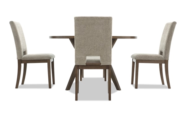 Dining set with a round wooden table and three beige upholstered chairs featuring wooden legs and a modern design.