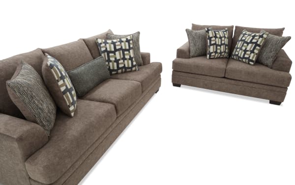 Two brown fabric sofas with plush cushions and patterned throw pillows, showcasing modern living room seating furniture.