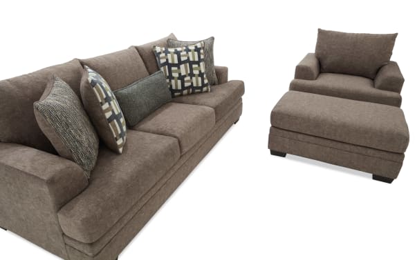 Brown fabric sofa set with a three-seater couch and matching armchair with ottoman, featuring patterned and textured throw pillows for living room seating.