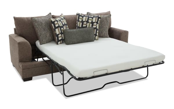 Brown fabric sofa sleeper with a white mattress and five decorative pillows, featuring a metal frame for easy bed conversion.
