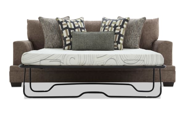 Brown fabric sofa bed with a black metal frame mattress support, featuring six decorative pillows in geometric and textured patterns, ideal for small living spaces.