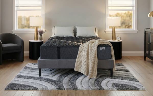 Lush 13'' Queen Extra Firm Standard Mattress Set in dark gray with quilted top, layered foam and spring coil system on gray upholstered platform bed, styled with beige knit throw and white pillows in modern bedroom.