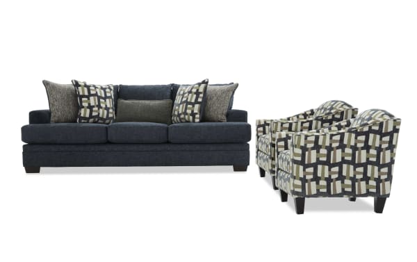 Dark blue fabric sofa with six patterned and textured throw pillows, paired with two matching armchairs featuring geometric multicolor upholstery and dark wooden legs.