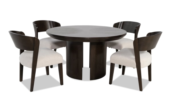 Dark wood round dining table with four matching chairs featuring beige upholstered seats and curved backrests, modern contemporary style.