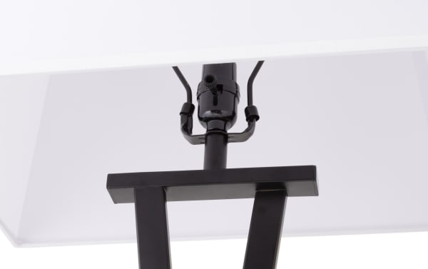Close-up of a modern black metal lamp holder with a white fabric lampshade, highlighting the socket and support structure.