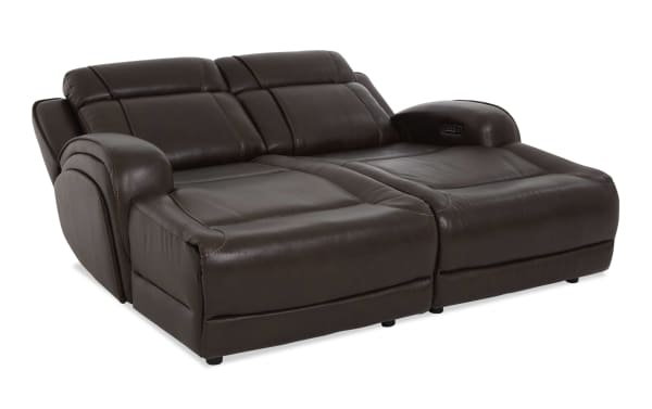 Dark brown leather reclining loveseat with padded armrests and cushioned backrests, designed for comfort and relaxation in living rooms.