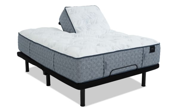 Adjustable bed base with a gray fabric frame and white quilted mattress, featuring a raised head section for customizable comfort.