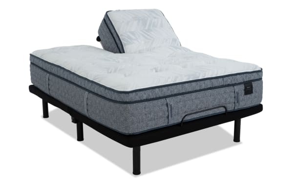 Adjustable bed base with gray fabric frame and white patterned mattress, featuring a raised backrest for customizable comfort.