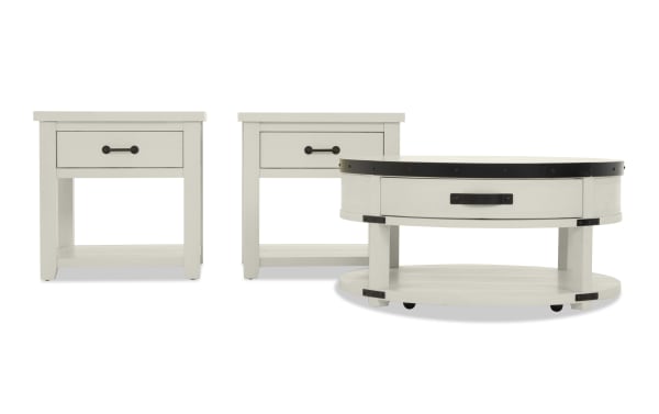 Set of white wooden rustic-style furniture including two square side tables and one round coffee table with black metal accents and drawer handles.