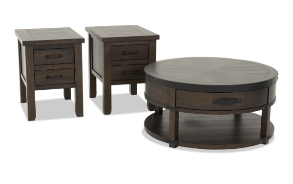 Set of three dark brown wooden furniture pieces including two rectangular end tables with two drawers each and a round coffee table with a drawer and lower shelf, featuring metal accents and rustic design.