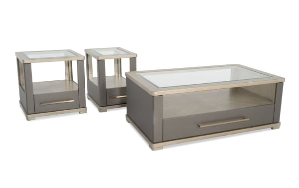 Set of modern gray leather and brushed metal coffee and side tables with glass tops, featuring storage drawers and open shelves for living room decor.