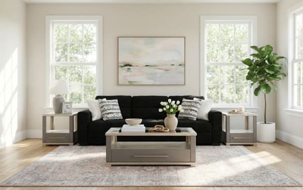 Modern living room with a black fabric sofa, gray wooden coffee and side tables, white tulip vase, abstract wall art, and large windows.