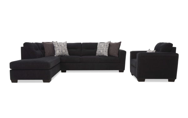 Dark charcoal gray fabric sectional sofa with chaise lounge and matching armchair, featuring tufted cushions and patterned throw pillows for modern living rooms.
