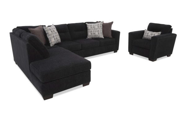 Black fabric sectional sofa with chaise lounge and matching armchair, featuring dark wooden legs and decorative patterned and solid throw pillows for modern living room seating.