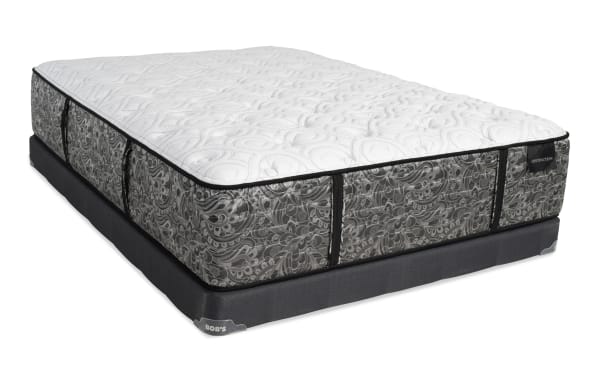 Mattress and foundation set with a white quilted top and gray patterned sides, featuring black trim and corner tags labeled "DISTINCTION" and "BOB'S."