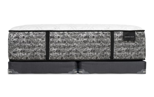 Mattress with black and white paisley pattern sides and white quilted top, labeled "DISTINCTION," placed on two dark gray box springs with "BOB'S" branding.