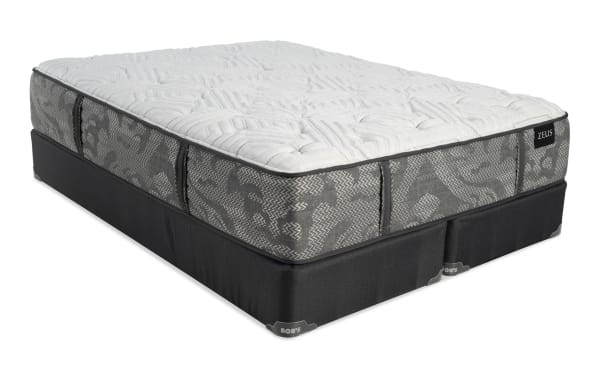 Queen-size Zeus mattress with gray patterned fabric sides and white quilted top, resting on a black Bob's foundation base.