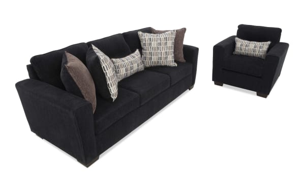 Dark gray fabric sofa and armchair set with plush cushions, featuring patterned and solid throw pillows, ideal for modern living rooms.