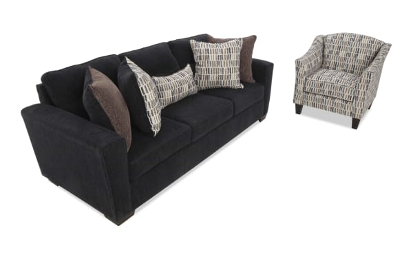 Modern living room set featuring a black fabric sofa with three seat cushions and patterned accent pillows, paired with a matching patterned armchair.