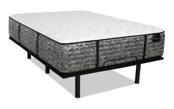 Mattress with white quilted top and gray floral patterned sides on a black metal bed frame with legs, featuring the brand label "DISTINCTION" on the side.