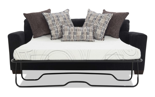 Black fabric sofa bed with metal frame pull-out mattress, featuring five decorative pillows in brown and patterned beige tones, modern design.