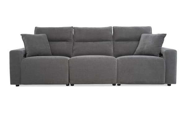 Modern gray fabric reclining sofa with three seats, padded backrests, and two matching throw pillows, ideal for living room comfort.