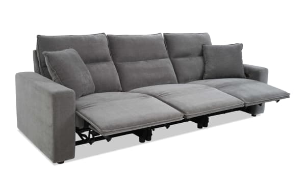 Modern gray fabric reclining sofa with three seats, padded armrests, and two matching cushions, designed for comfort and relaxation.
