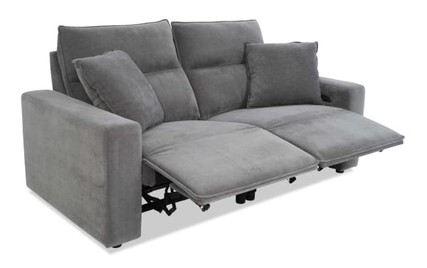 Modern gray fabric reclining loveseat with plush cushions and two reclining footrests, designed for comfort and relaxation.